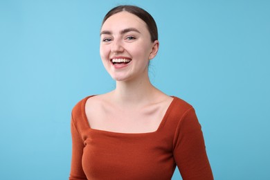 Photo of Beautiful woman laughing on light blue background. Positive emotion