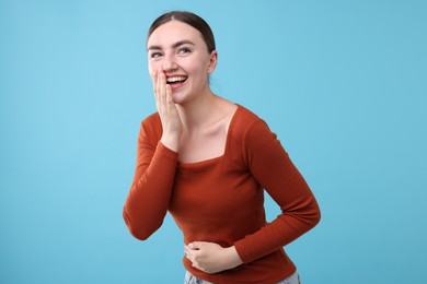 Photo of Beautiful woman laughing on light blue background. Positive emotion