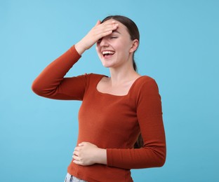 Photo of Beautiful woman laughing on light blue background. Positive emotion