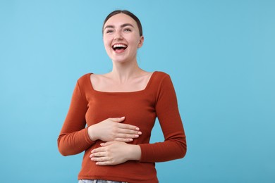 Photo of Beautiful woman laughing on light blue background. Positive emotion