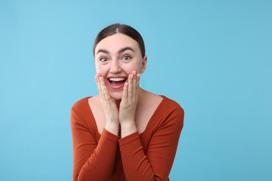Photo of Beautiful woman laughing on light blue background. Positive emotion