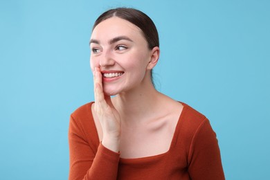 Photo of Beautiful woman laughing on light blue background. Positive emotion