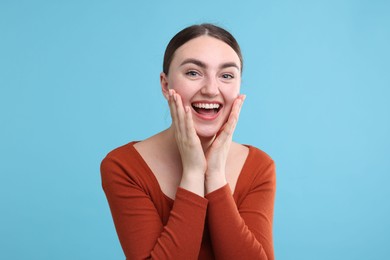 Photo of Beautiful woman laughing on light blue background. Positive emotion