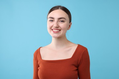 Photo of Beautiful woman laughing on light blue background. Positive emotion