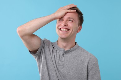 Photo of Handsome man laughing on light blue background. Positive emotion