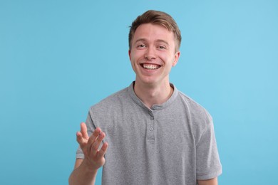 Photo of Handsome man laughing on light blue background. Positive emotion