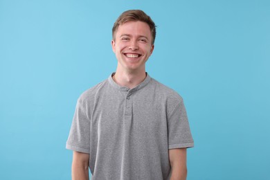 Photo of Handsome man laughing on light blue background. Positive emotion