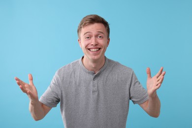 Photo of Handsome man laughing on light blue background. Positive emotion