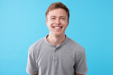 Photo of Handsome man laughing on light blue background. Positive emotion