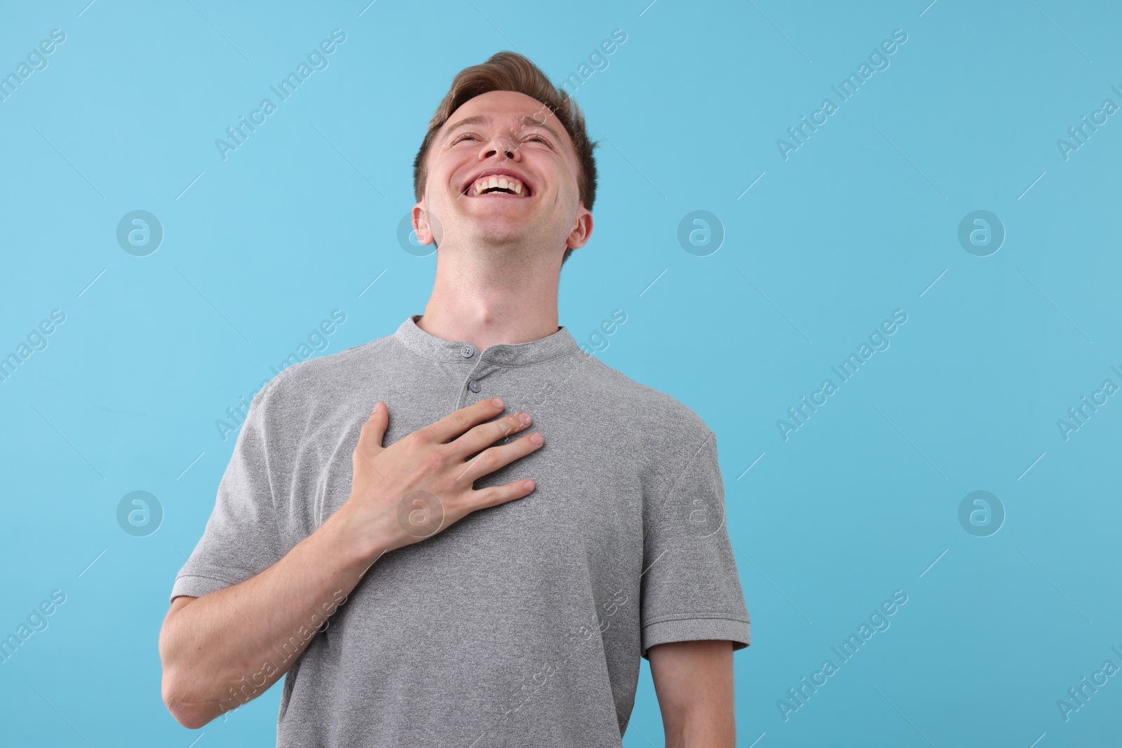Handsome man laughing on light blue background. Positive emotion Photo of Handsome man laughing on light blue background. Positive emotion