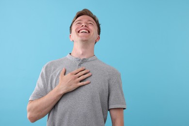 Photo of Handsome man laughing on light blue background. Positive emotion