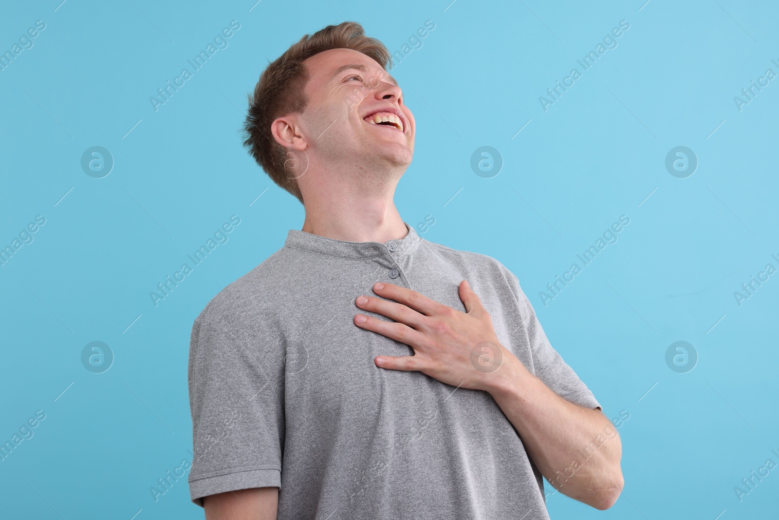 Handsome man laughing on light blue background. Positive emotion Photo of Handsome man laughing on light blue background. Positive emotion