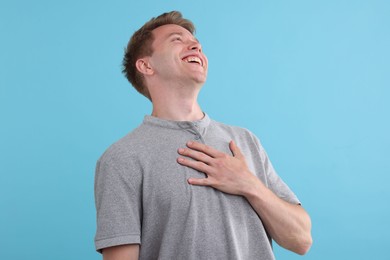 Photo of Handsome man laughing on light blue background. Positive emotion