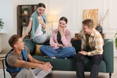 Photo of Friends laughing on sofa indoors. Positive emotion