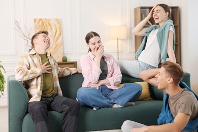 Photo of Friends laughing on sofa indoors. Positive emotion