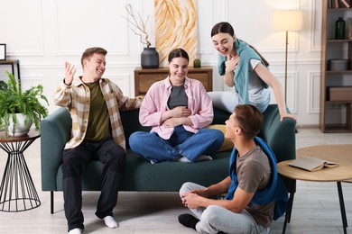Photo of Friends laughing on sofa indoors. Positive emotion