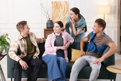 Photo of Friends laughing on sofa indoors. Positive emotion