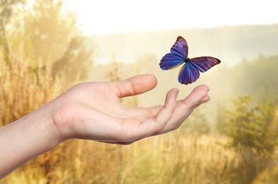 Image of Hope. Butterfly flying from woman's hand in nature, closeup