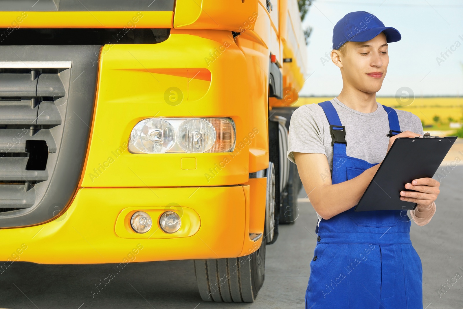 Image of Car service worker with clipboard and truck outdoors