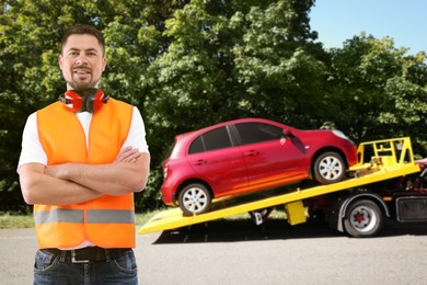 Image of Car service worker near red auto and tow truck outdoors