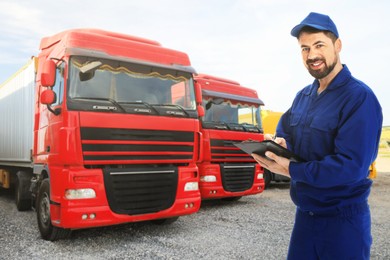 Image of Car service worker with clipboard and trucks outdoors