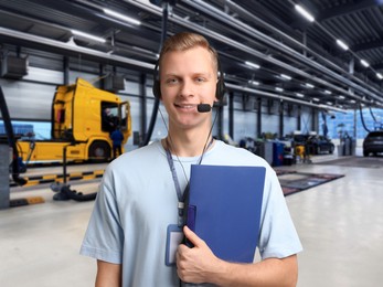 Image of Car service worker with headset and clipboard against truck at station. Client support