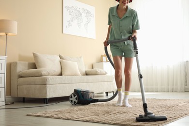 Photo of Woman cleaning carpet with vacuum cleaner at home, closeup