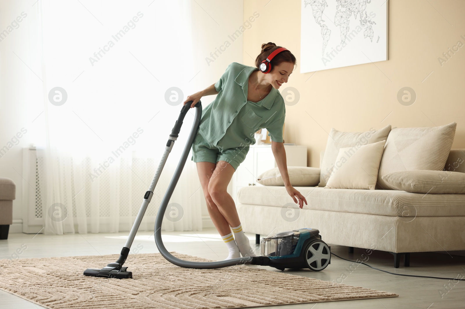 Woman in headphones cleaning carpet with vacuum cleaner at home Photo of Woman in headphones cleaning carpet with vacuum cleaner at home