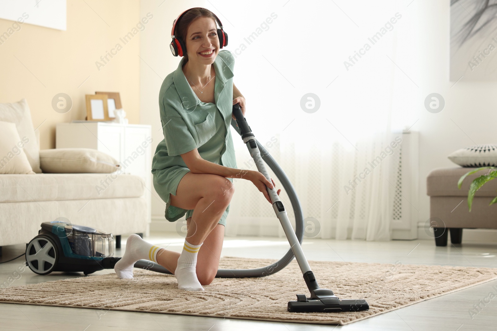 Woman in headphones cleaning carpet with vacuum cleaner at home Photo of Woman in headphones cleaning carpet with vacuum cleaner at home