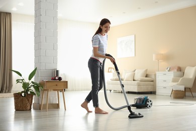Photo of Woman cleaning floor with vacuum cleaner at home
