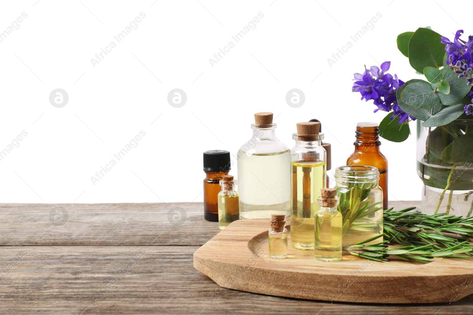 Photo of Bottles of essential oils and different plants on wooden table against white background