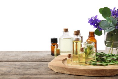 Photo of Bottles of essential oils and different plants on wooden table against white background
