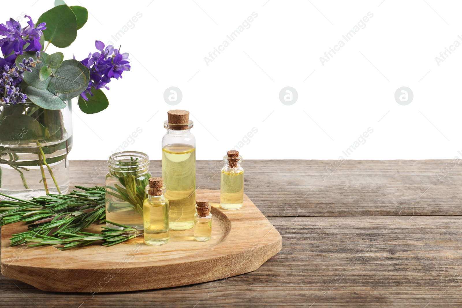 Photo of Bottles of essential oils and different plants on wooden table against white background