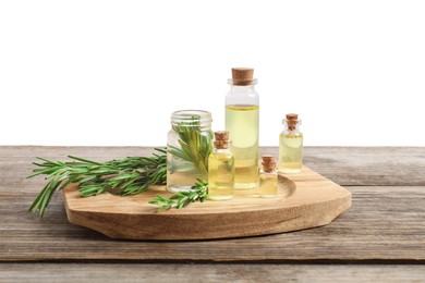 Photo of Bottles of essential oils and rosemary on wooden table against background