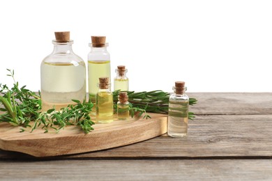 Photo of Bottles of essential oils, thyme and rosemary on wooden table against background