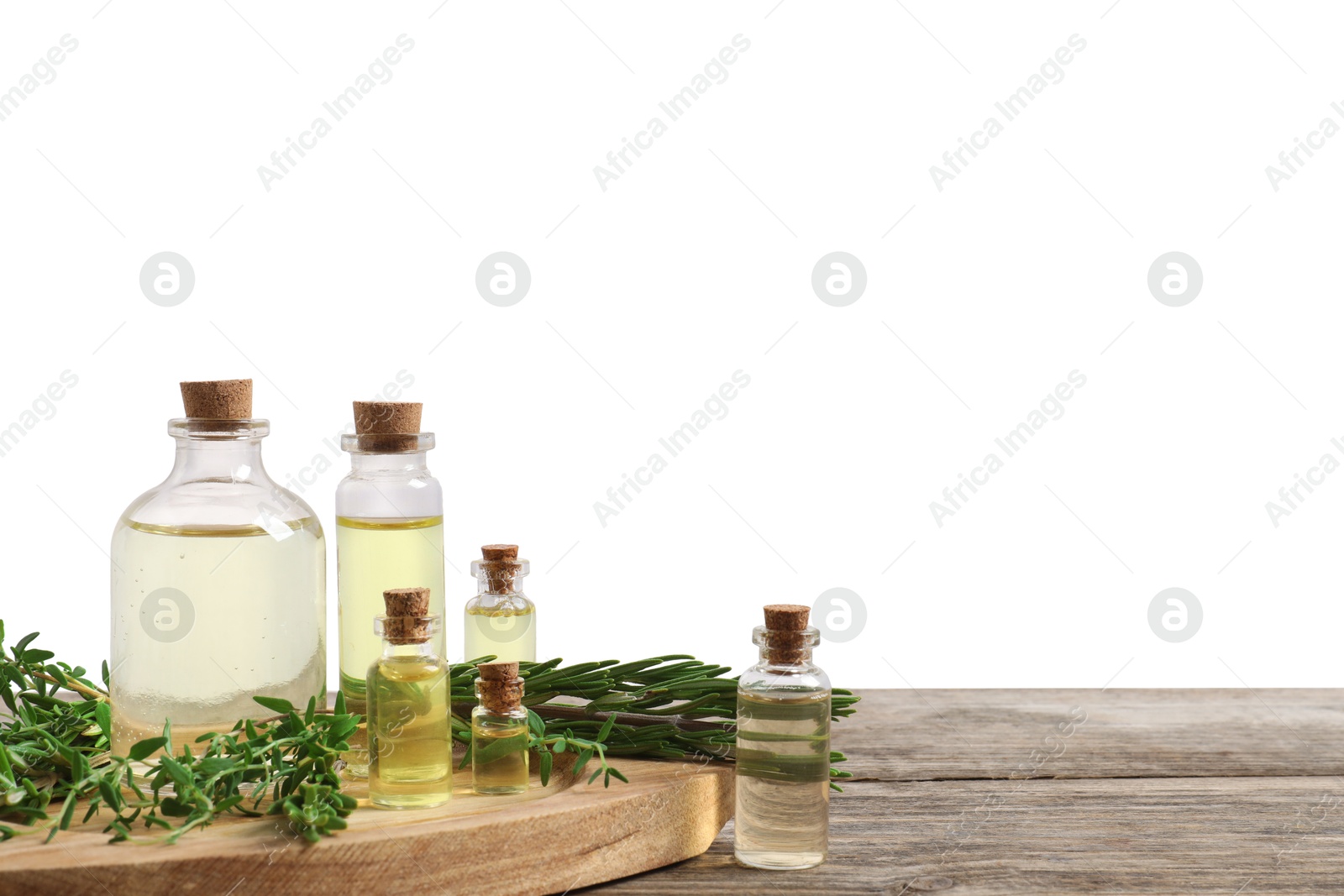 Photo of Bottles of essential oils, thyme and rosemary on wooden table against background