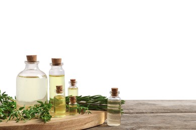 Photo of Bottles of essential oils, thyme and rosemary on wooden table against background