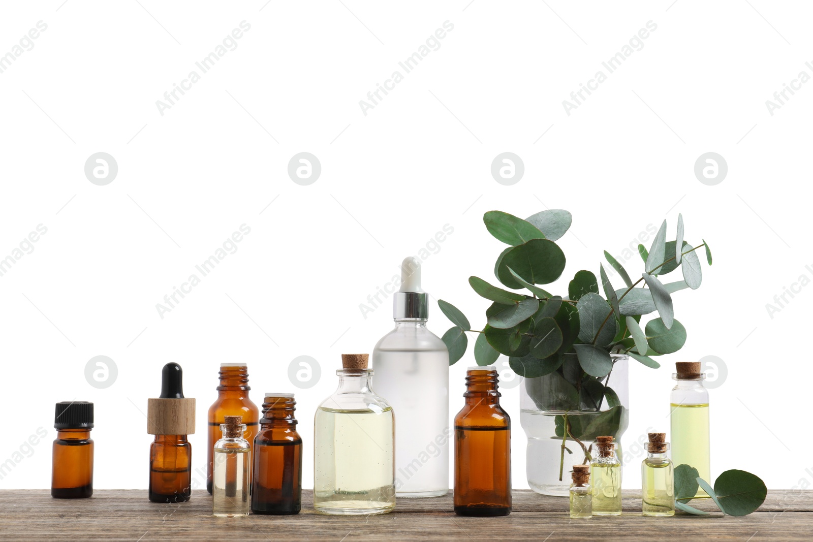 Photo of Bottles of essential oils and eucalyptus branches on wooden table against background