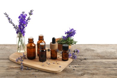 Photo of Bottles of essential oils and different plants on wooden table against white background