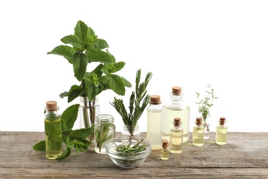 Photo of Bottles of essential oils and different herbs on wooden table against white background