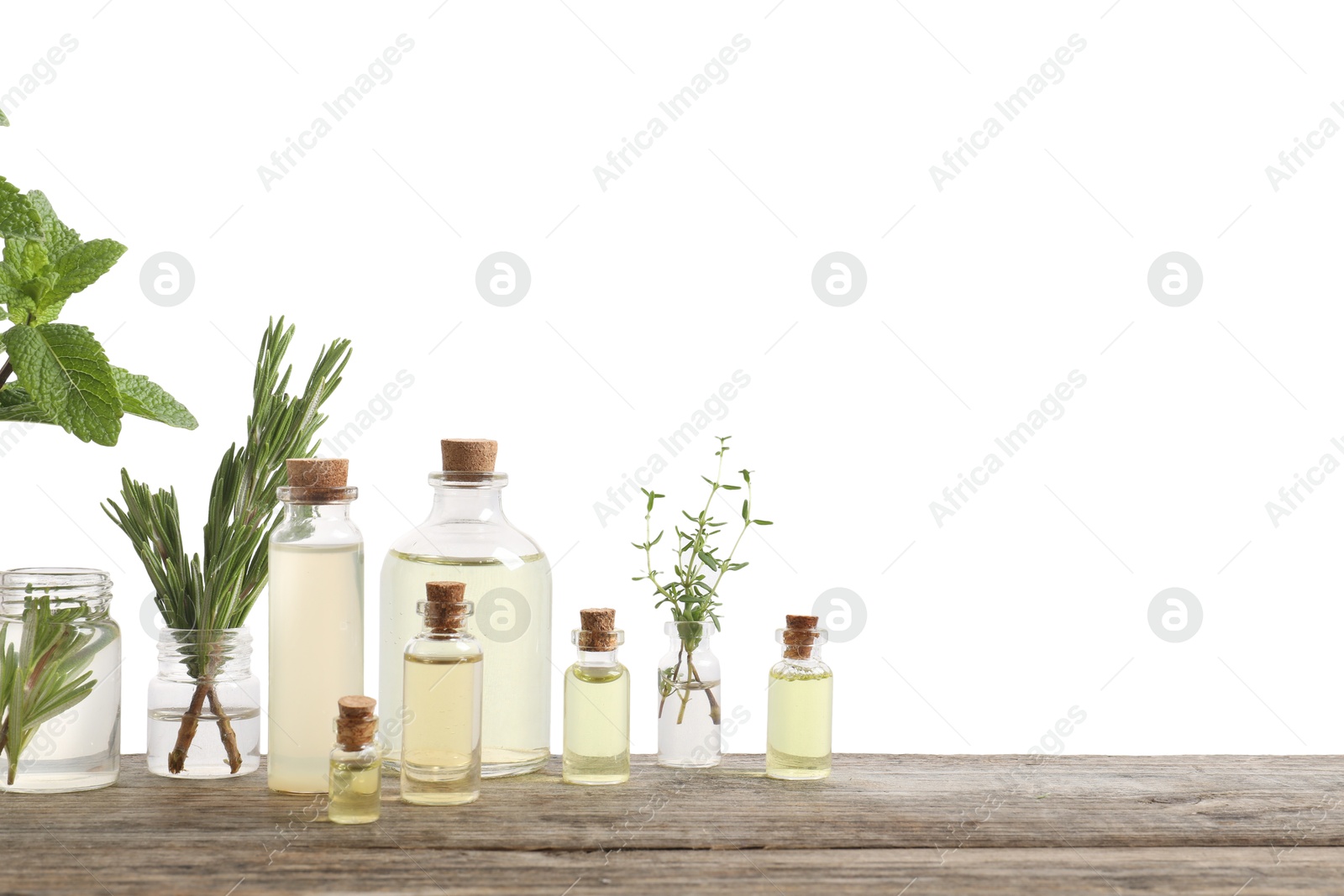 Photo of Bottles of essential oils and different herbs on wooden table against white background