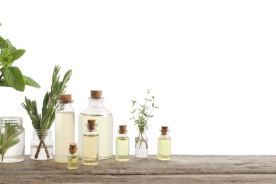 Photo of Bottles of essential oils and different herbs on wooden table against white background