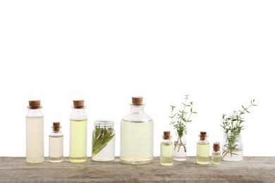 Photo of Bottles of essential oils, rosemary and thyme on wooden table against white background