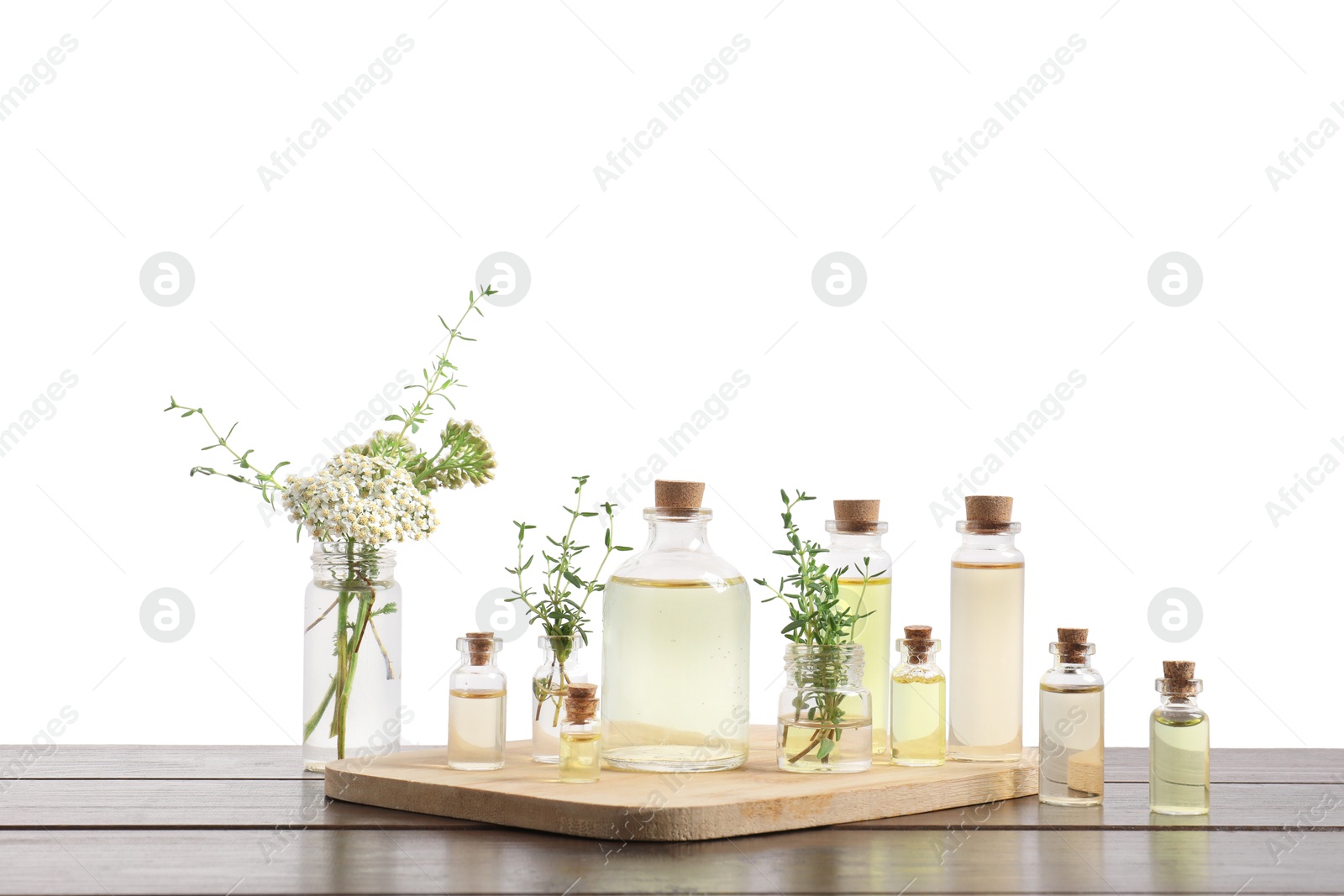 Photo of Bottles of essential oils and different herbs on wooden table against white background