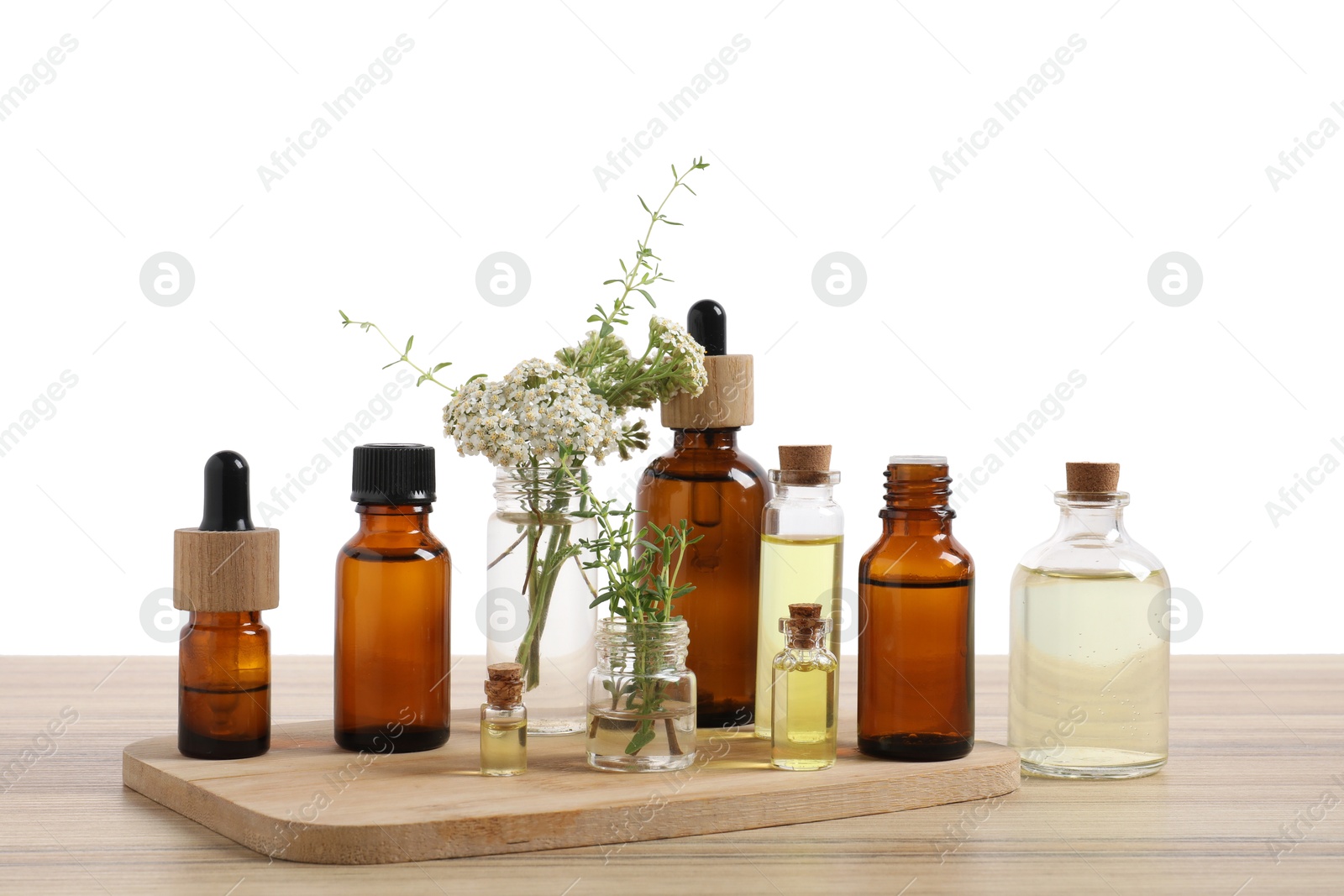 Photo of Bottles of essential oils and different herbs on wooden table against white background