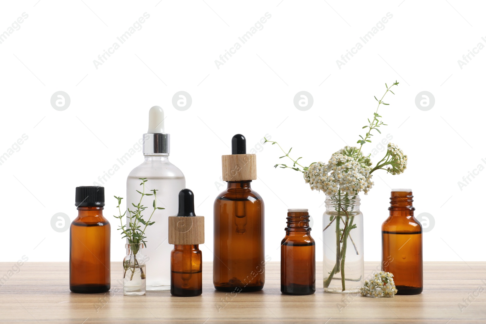 Photo of Bottles of essential oils and different herbs on wooden table against white background