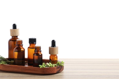 Photo of Bottles of essential oils and different herbs on wooden table against white background