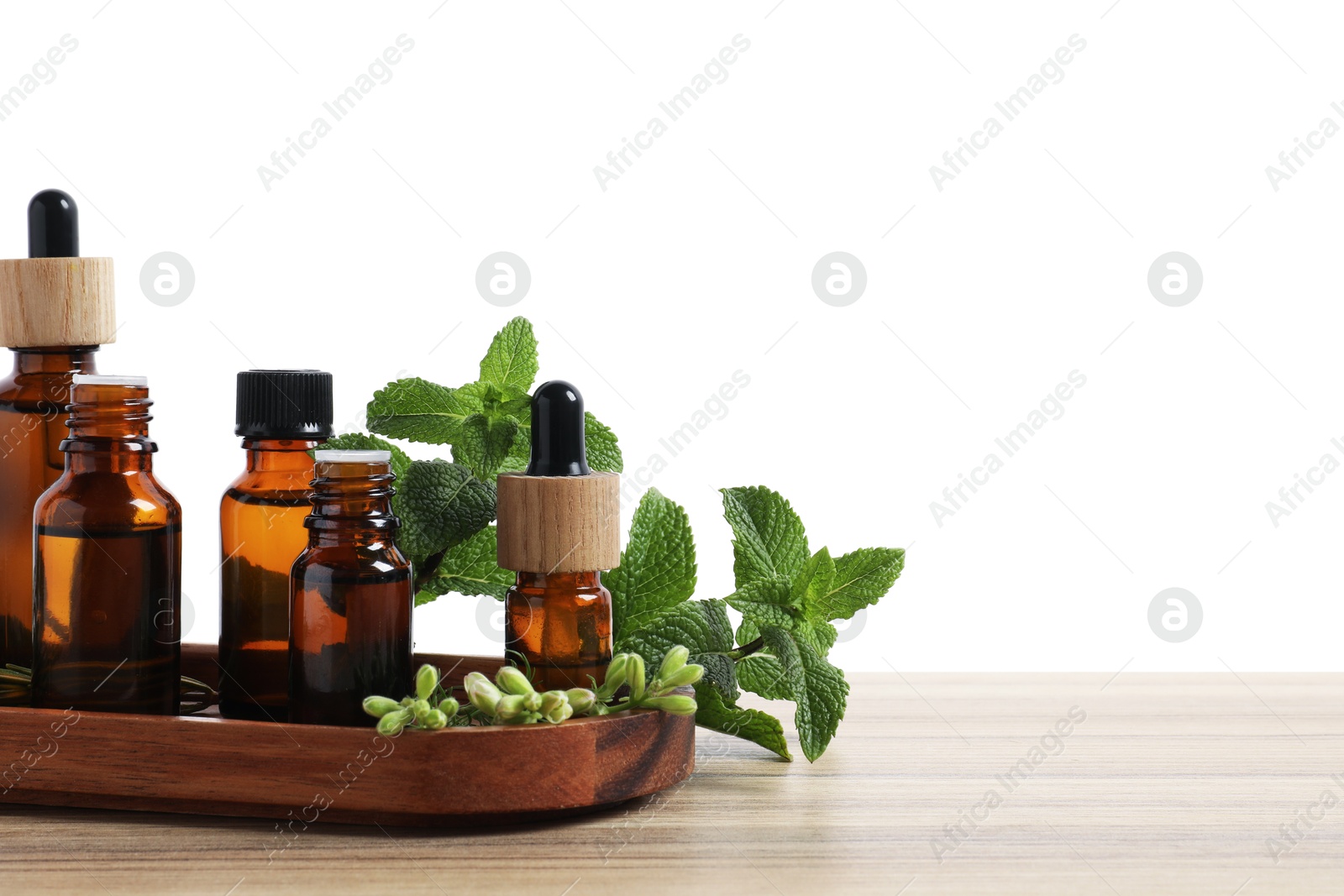 Photo of Bottles of essential oils and different herbs on wooden table against white background