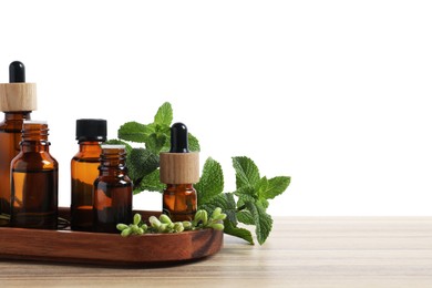 Photo of Bottles of essential oils and different herbs on wooden table against white background