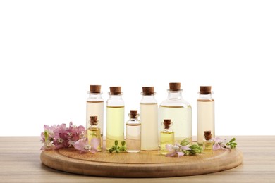 Photo of Bottles of essential oils and different plants on wooden table against white background